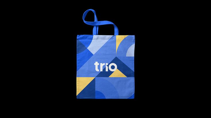 a blue and yellow shopping bag with the word trio printed on it, against a black background