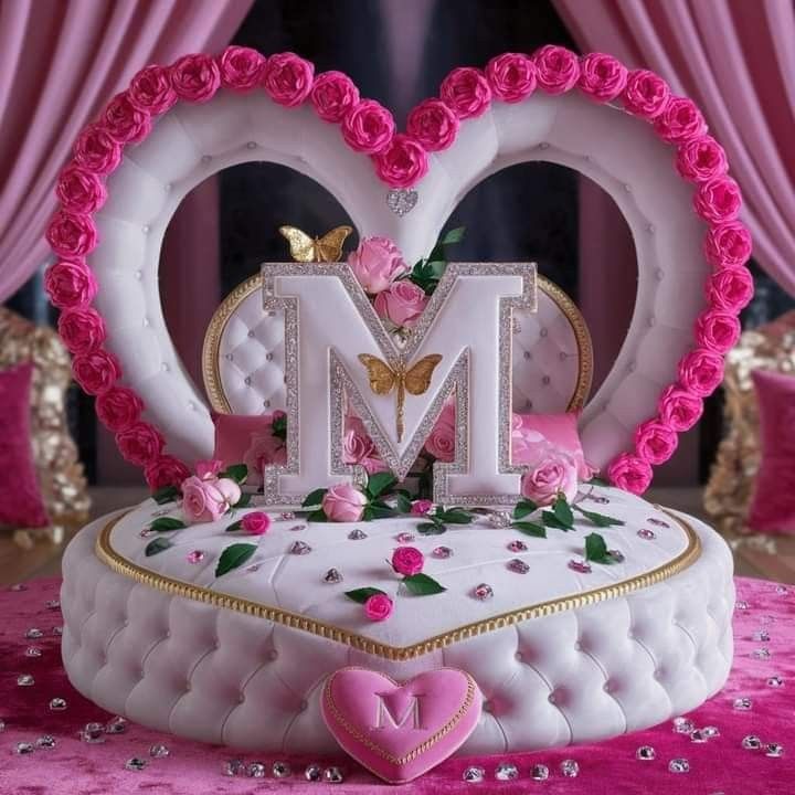 a heart shaped cake with pink roses on it and the letter m in the middle