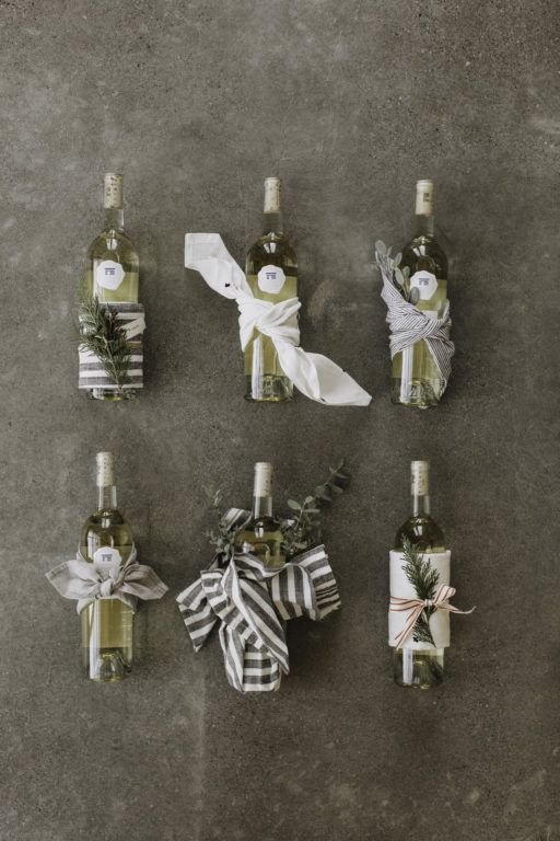 six wine bottles wrapped in paper and tied with bows