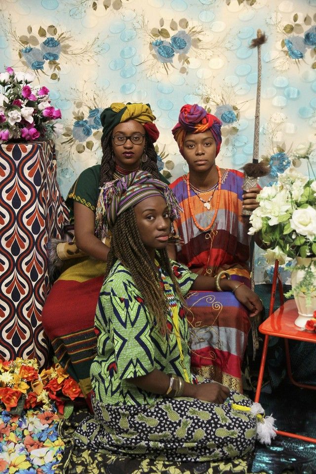 three women are sitting in front of a floral wall