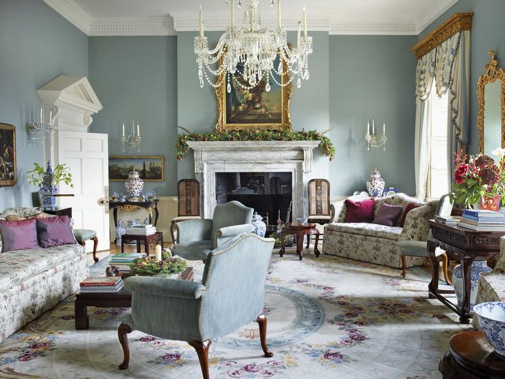 a living room filled with furniture and a chandelier hanging from the ceiling over a fire place