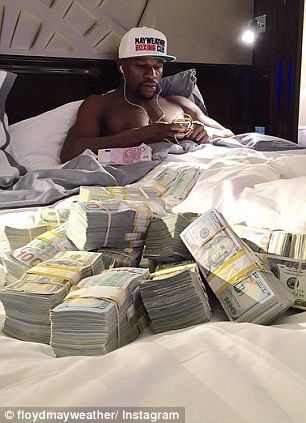 a man laying in bed with stacks of money