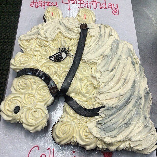 a cake shaped like a horse with white frosting and black ribbon around its neck