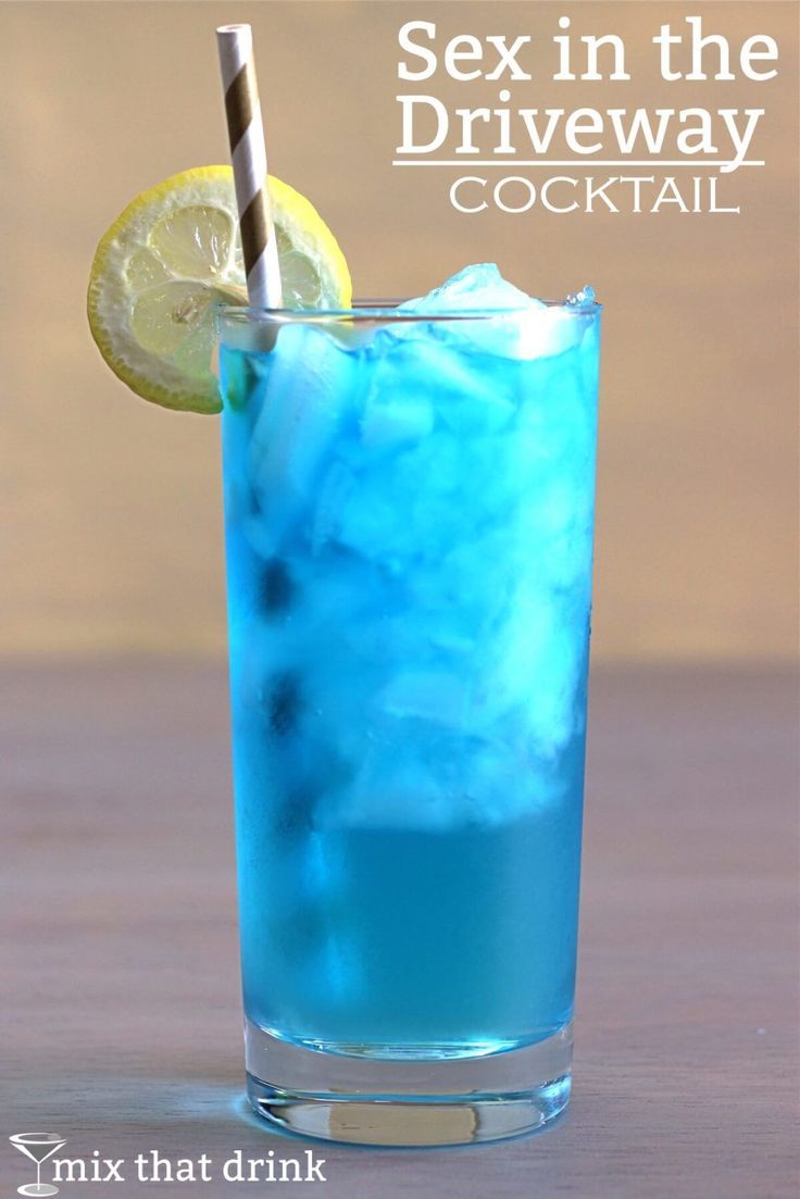 a blue drink with ice, lemon and a straw sitting on a table next to a slice of lemon