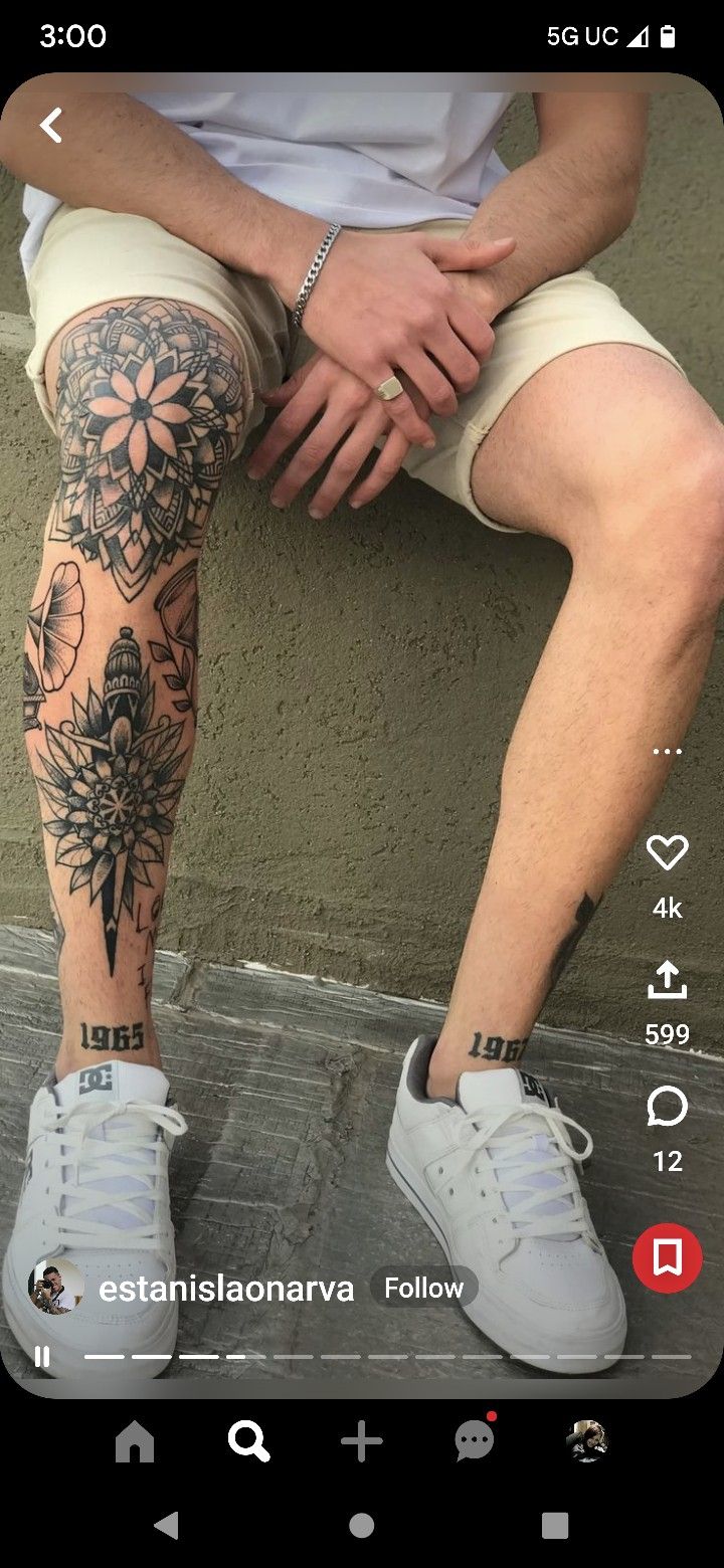 a person sitting on the ground with their legs crossed and tattoos on his leg,