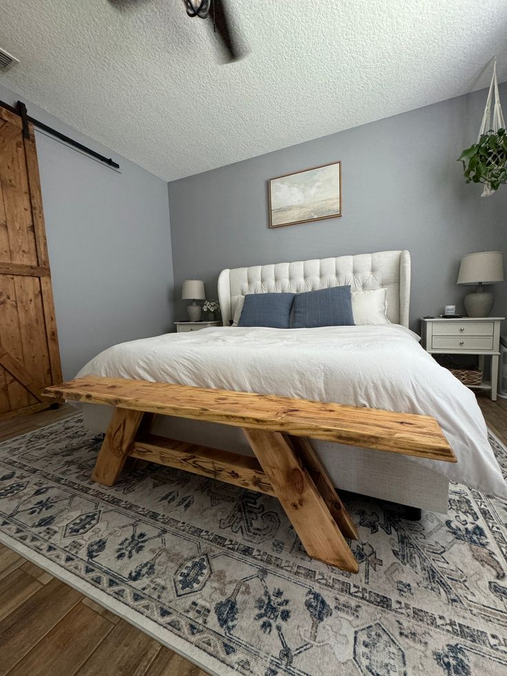 a bed with a wooden bench sitting on top of it's headboard in a bedroom