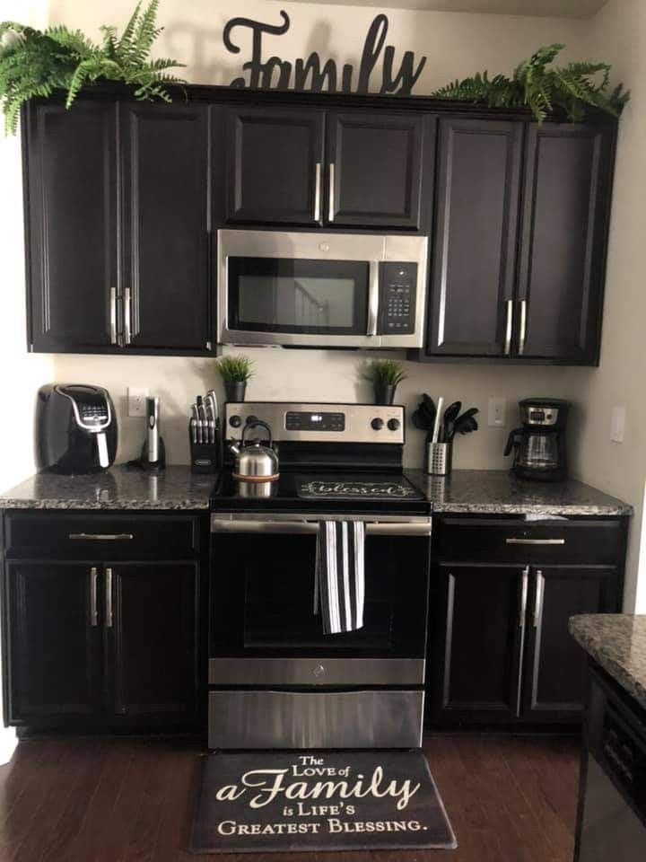 a kitchen with black cabinets and stainless steel appliances, including an oven, microwave, dishwasher, toaster, and coffee maker