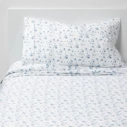 a white bed with blue flowers on it and two pillow cases next to each other