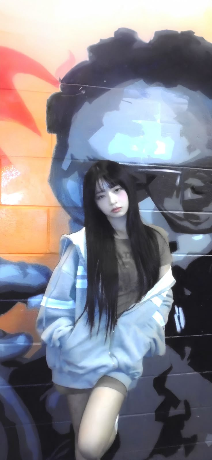 a woman with long black hair sitting in front of a painting