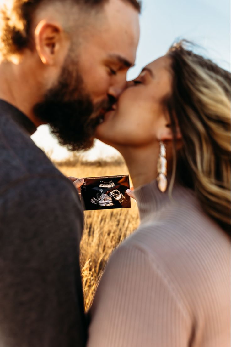 a man and woman kissing each other while holding an object in front of their face