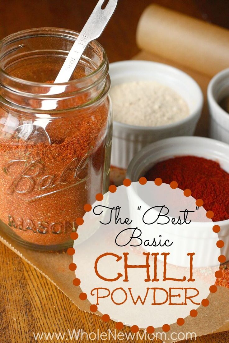 three jars filled with red chili powder and spices on top of a wooden cutting board