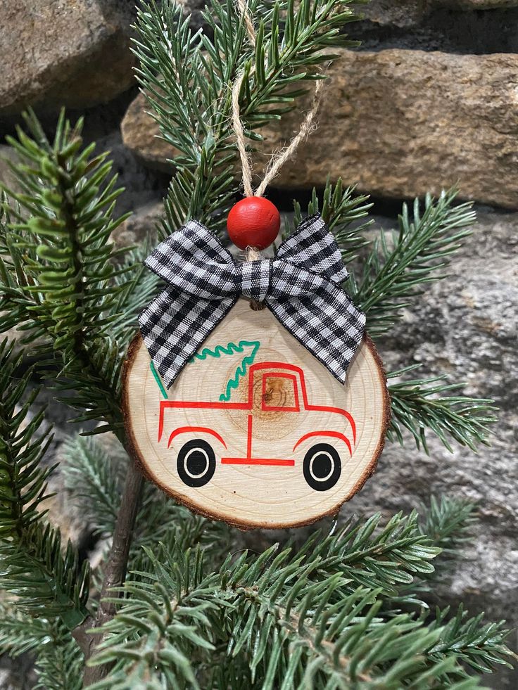 a wooden ornament with a red truck on it hanging from a pine tree