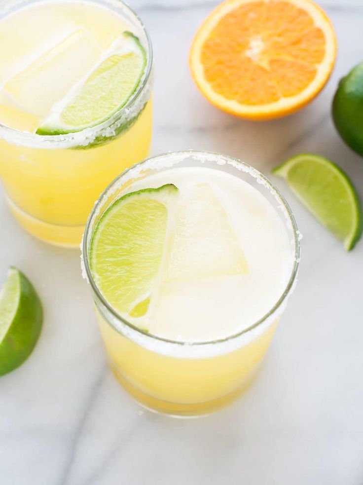 two glasses filled with lemonade and limes