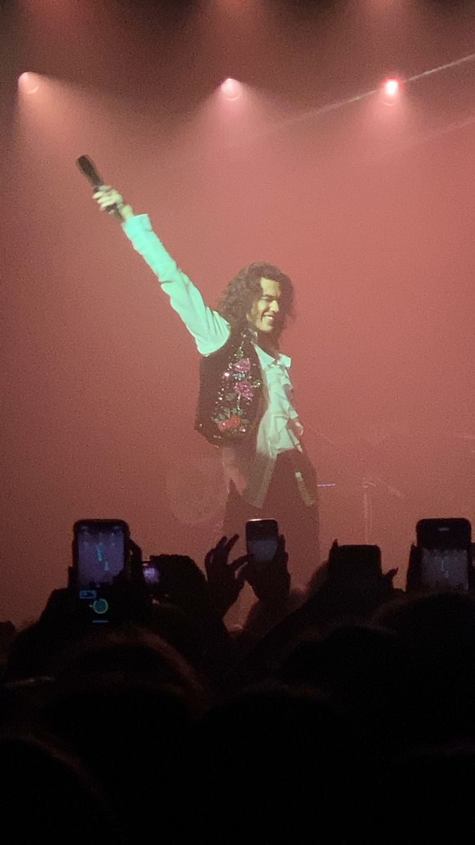 a man standing on top of a stage with his arms in the air as he sings