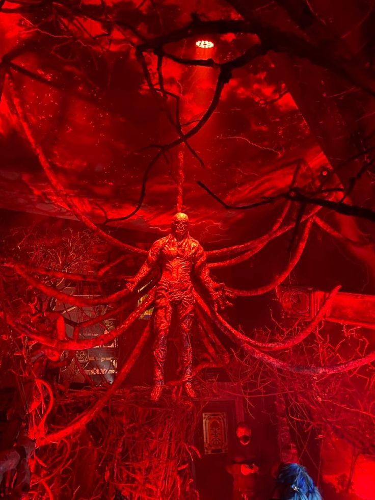 a creepy looking room with red lights and wires on the ceiling, in which there is a man standing