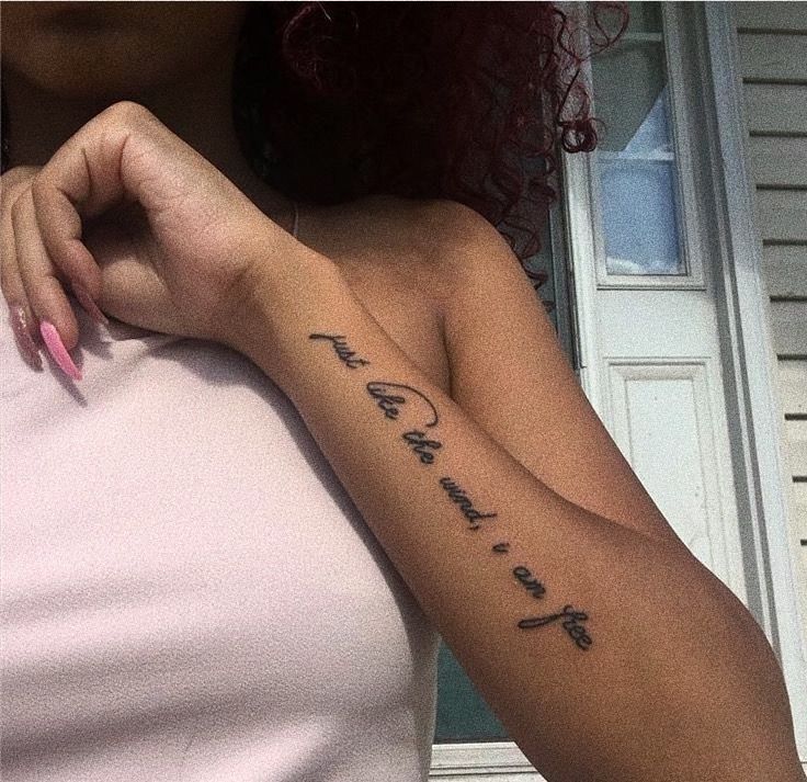 a woman with a cross tattoo on her left arm and the word faith written in cursive font