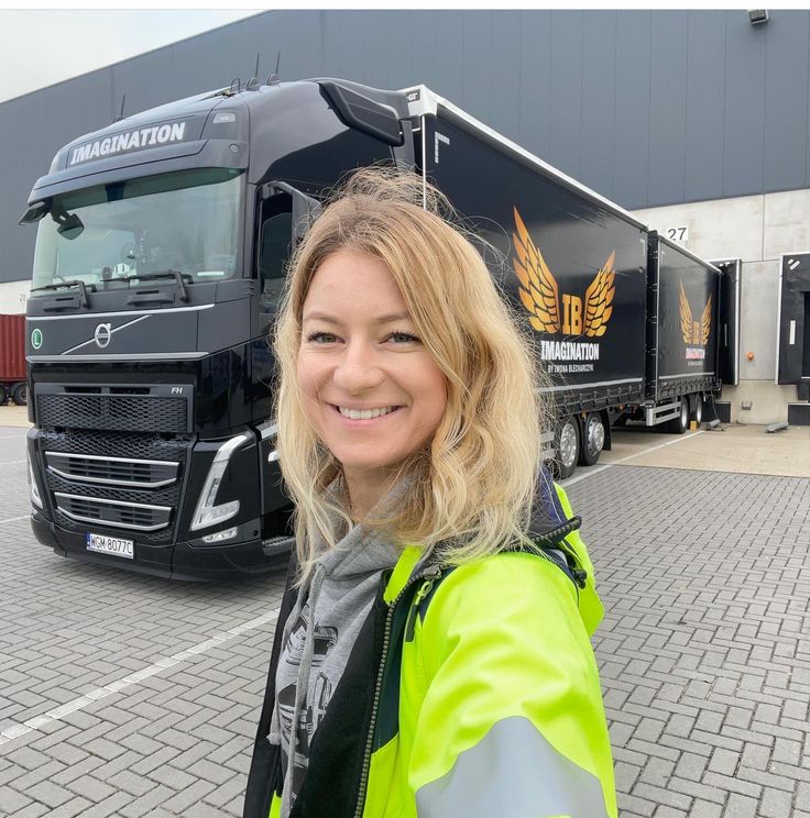 a woman standing in front of a semi truck