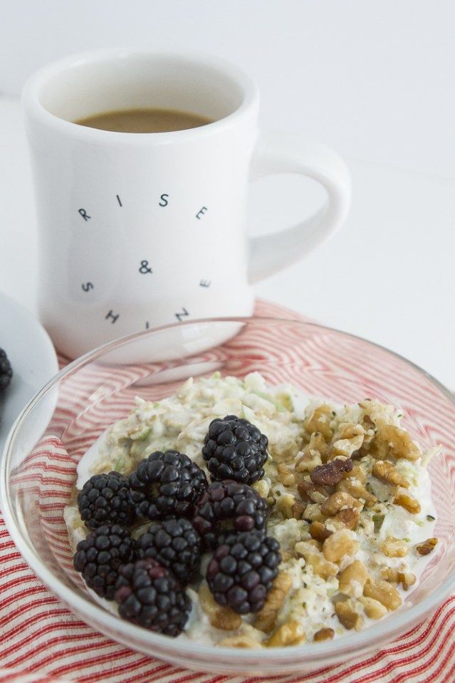 a bowl of cereal and berries next to a cup of coffee on a red and white table cloth