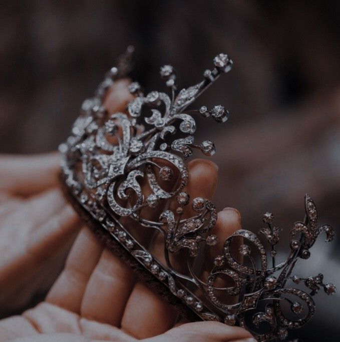 a close up of a person holding a tiara in their hand with other hands