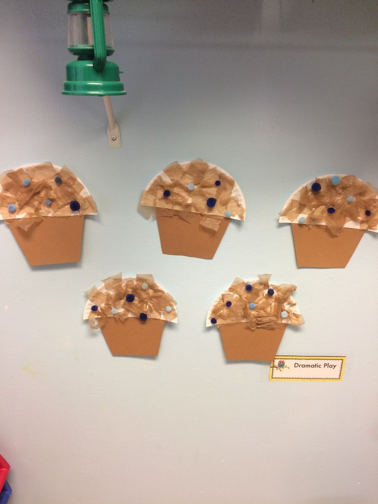 four cupcakes made out of brown paper on a white board with blue dots