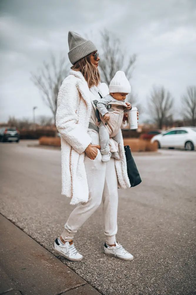 a woman is walking down the street with her baby in her arms and she is wearing white