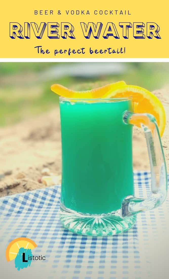 a pitcher filled with blue liquid sitting on top of a table next to a slice of orange