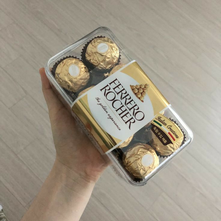 a person holding up a box of chocolates in their left hand and the top one is gold