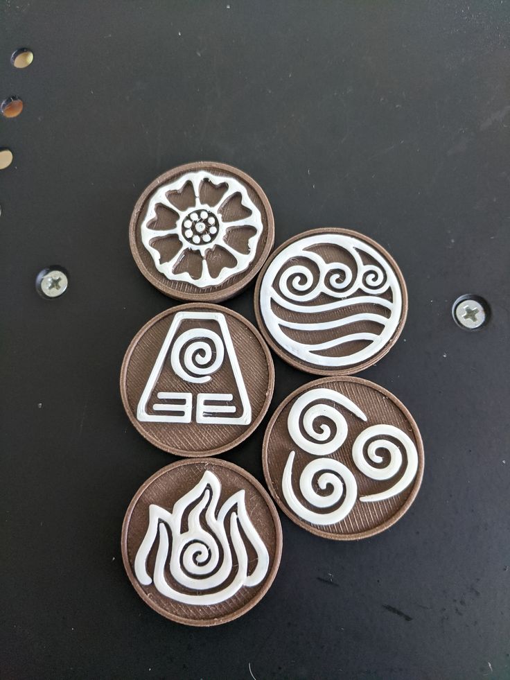 four clay coasters with designs on them sitting on top of a black countertop