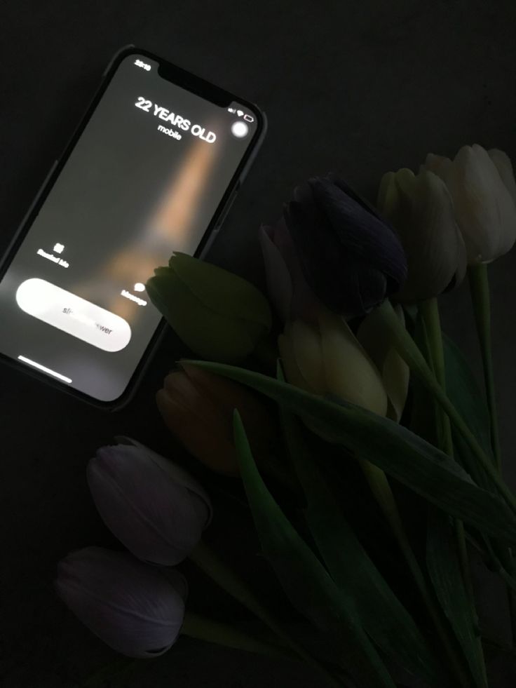 an iphone sitting on top of a table next to tulips