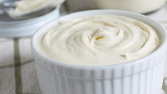 a white bowl filled with cream sitting on top of a table next to a bottle of milk