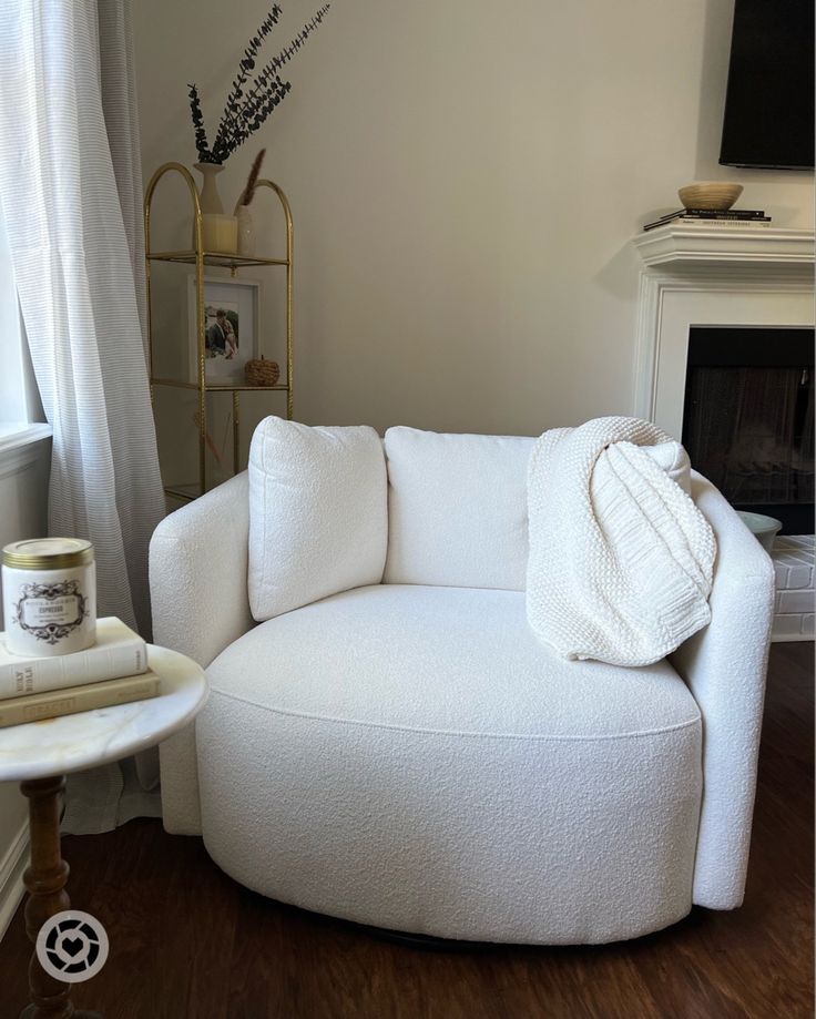 a white couch sitting in front of a fireplace next to a table with a candle on it