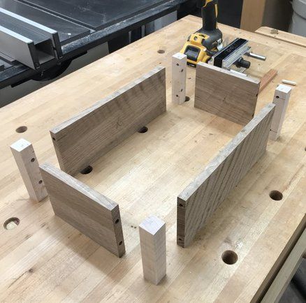 a wooden table with two pieces of wood on it and a drill bit in the middle