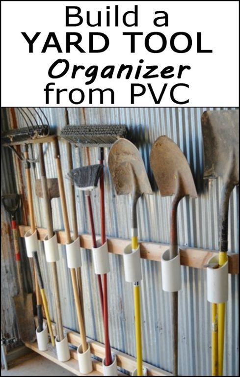 an organized tool rack with shovels and gardening implements hanging on the wall in front of it