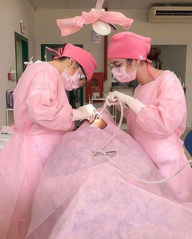 two women in pink scrubs are doing surgery