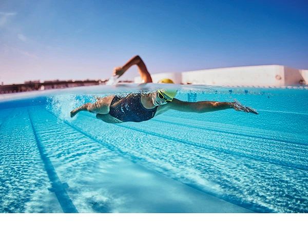 a man swimming in the water with his feet above the water's surface as he swims