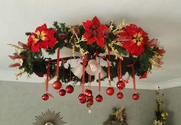 a chandelier decorated with poinsettis, bells and christmas decorations hanging from the ceiling