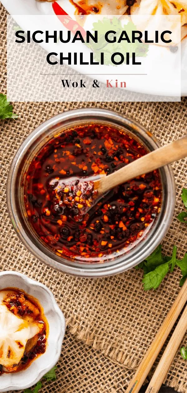 a bowl filled with chili sauce next to some chopsticks and other food items