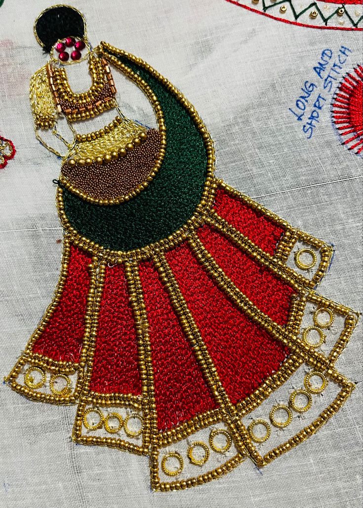 an embroidered piece with gold and red designs on it's side, sitting on top of a white table cloth