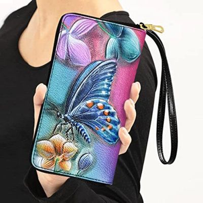 a woman holding a colorful wallet case with a butterfly on the front and flowers in the back