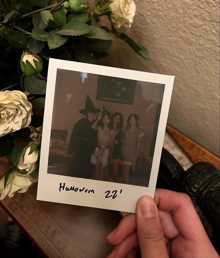 a person holding up a polaroid in front of a bouquet of flowers and roses