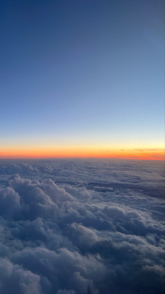 the view from an airplane looking down on some clouds and sky at sunset or dawn