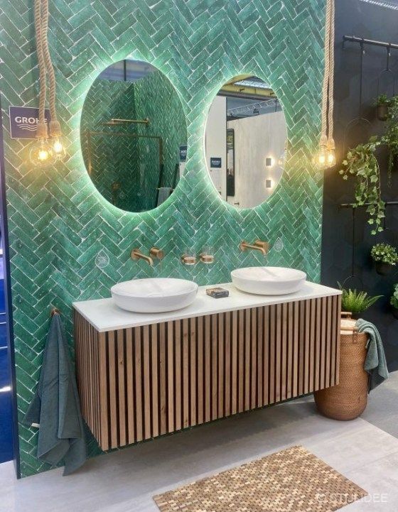 a bathroom with two sinks and mirrors on the wall next to a green tiled wall