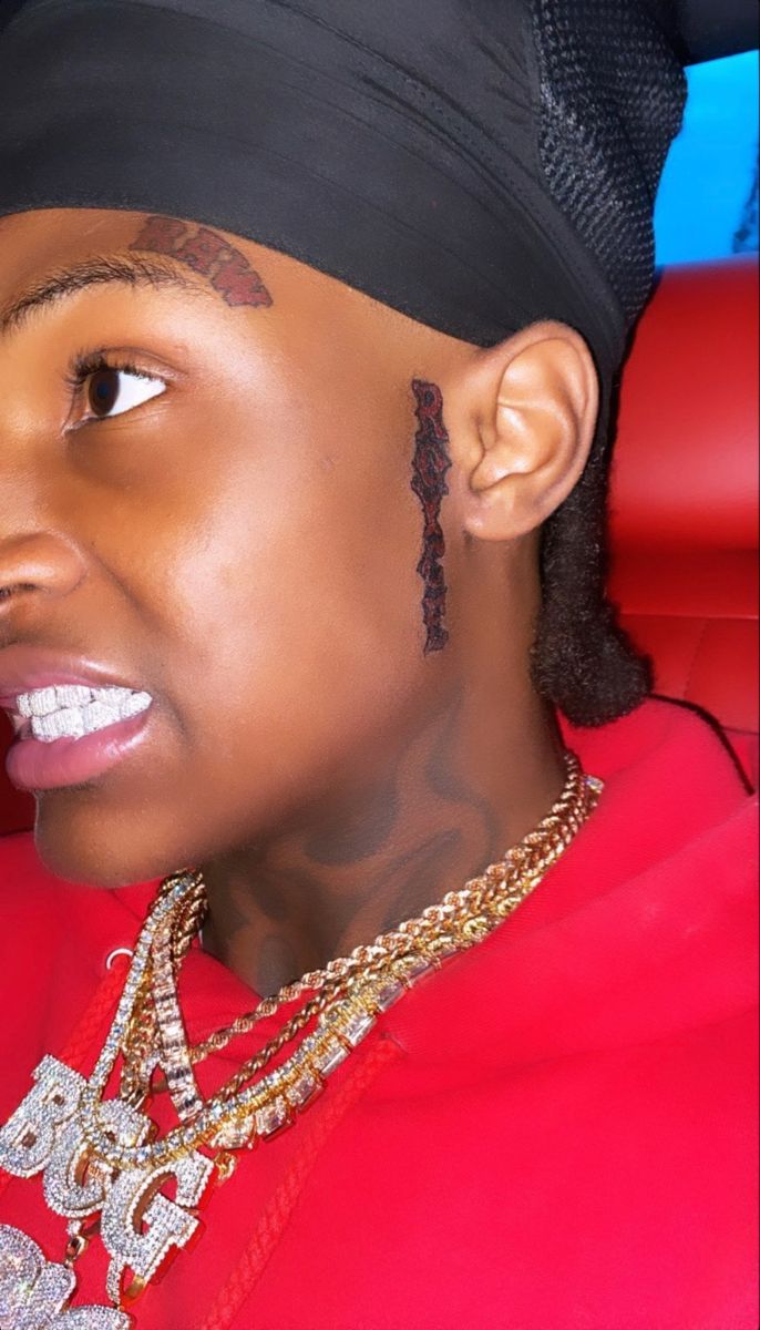 a woman with tattoos on her face and neck wearing a red shirt, black headband