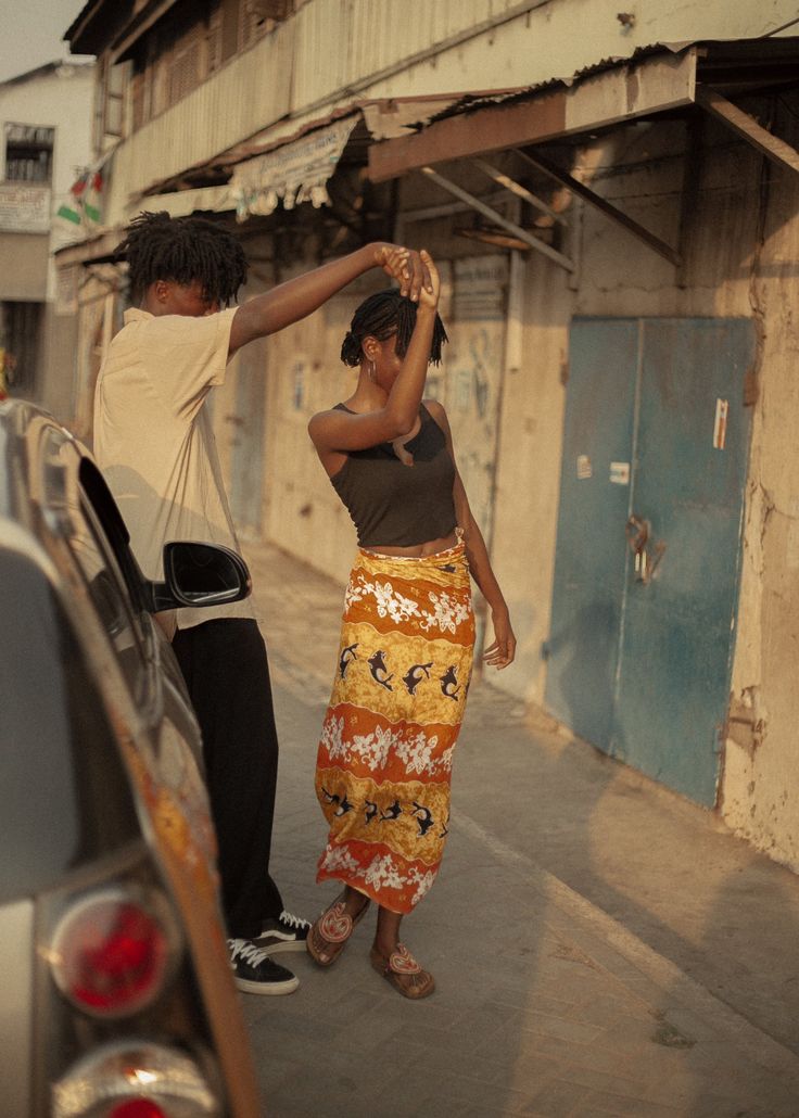 two people standing next to each other near a car