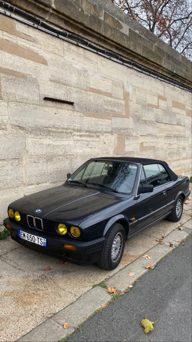 a black car parked next to a stone wall