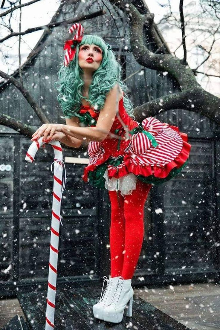 a woman dressed in christmas attire standing on top of a wooden platform with candy canes