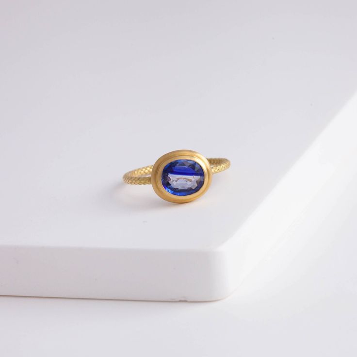 Description One-of-kind 18k yellow gold ring with a unique bi-color oval sapphire with darker and light blue hues, set in an east-west setting. The color of this sapphire is like seeing where the sky and the ocean meets at the horizon. This ring is in a rope design, adding a little more detail to every part of the ring. Details 18k Yellow Gold Size of sapphire – 7.1 x 6.1 x 2.8 mm (1.17 ct) Made in Japan *Please note that due to the natural quality of the stones, there may be inclusions, cracks, Yellow Sapphire Ring In Yellow Gold, Oval Gold Sapphire Ring, Timeless Blue Oval Sapphire Ring, Gold Oval Yellow Sapphire Ring, Oval Yellow Sapphire Ring In Yellow Gold, Oval Yellow Sapphire Ring In Gold, Timeless Yellow Gold Sapphire Ring, Oval Yellow Gold Sapphire Ring, Oval Cabochon Sapphire Ring With Center Stone