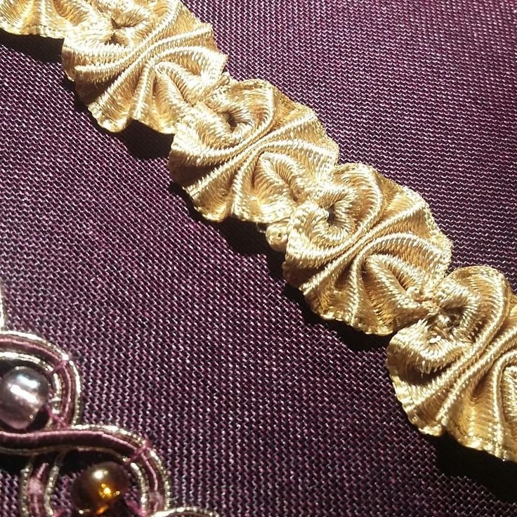 a close up of a piece of cloth with gold thread and beads on top of it