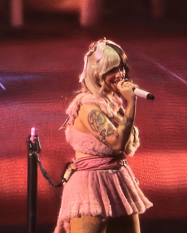 lady in pink outfit singing into microphone on stage