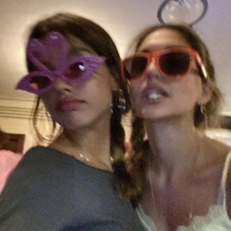 two women wearing sunglasses are posing for the camera